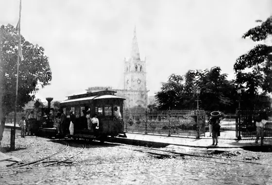 Parque Santander. Calle 10 con avenida 6. Se aprecia el tranvía que recorría las calles del centro de Cúcuta, la elegante verja de hierro que encerraba el parque importada de Alemania con 8 puertas y hermosos faroles que lo embellecían aún mas. Al fondo la Catedral de San José en construcción, que tenia en esa época solo una torre. 1897.