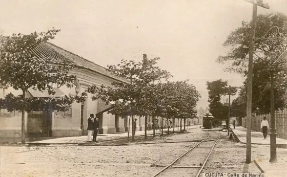 Calle Nariño (actualmente calle 10) con avenida Bolívar (actualmente avenida 6ª). Se pueden apreciar a la izquierda el almacén la Novedad lugar ocupado hoy en día por una sucursal de Foto Japón, a la derecha el enrejado del parque Santander y al fondo el tranvía. Foto donada por el doctor Virgilio Durán Martínez