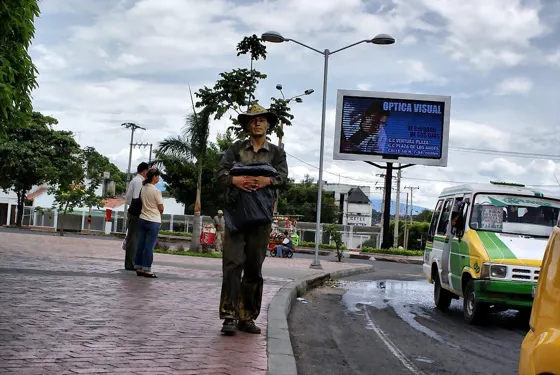 Vendedor en un andén con buseta al fondo