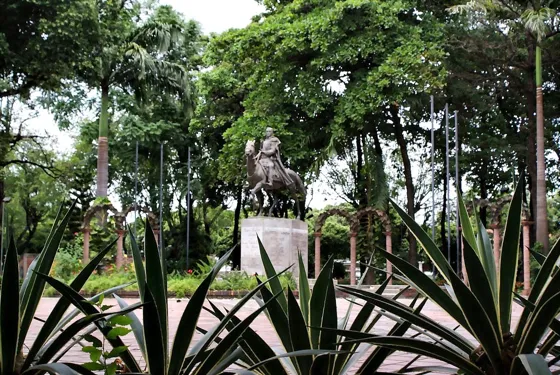 Estatua ecuestre entre agaves en un parque