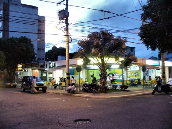 Esquina con palmeras y negocios al anochecer
