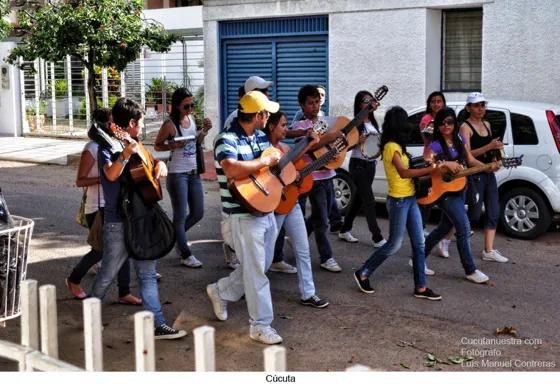 Jóvenes con guitarras caminando por una calle de Cúcuta
