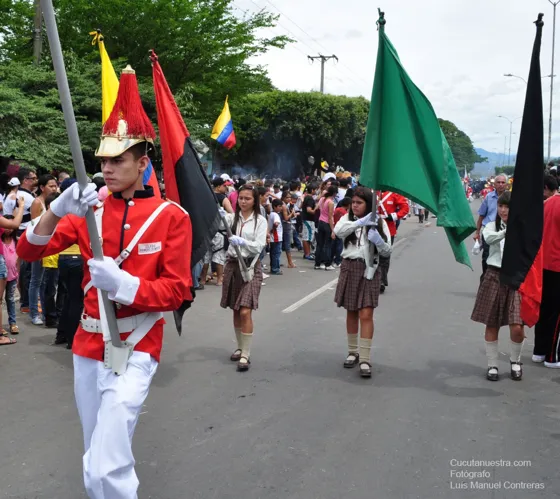 Banda de un colegio con uniforme rojo y banderas