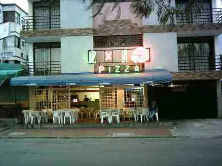Pizzería con mesas en la acera