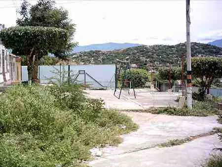 Parque de barrio con juegos infantiles y cerros al fondo