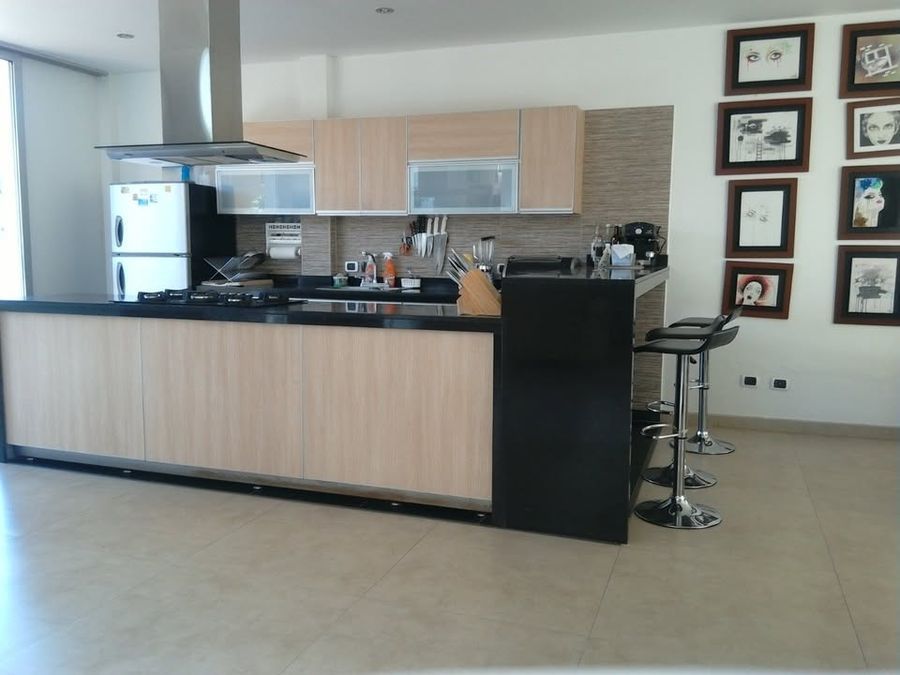 Cocina integral con barra en granito, campana extractora y sillas altas