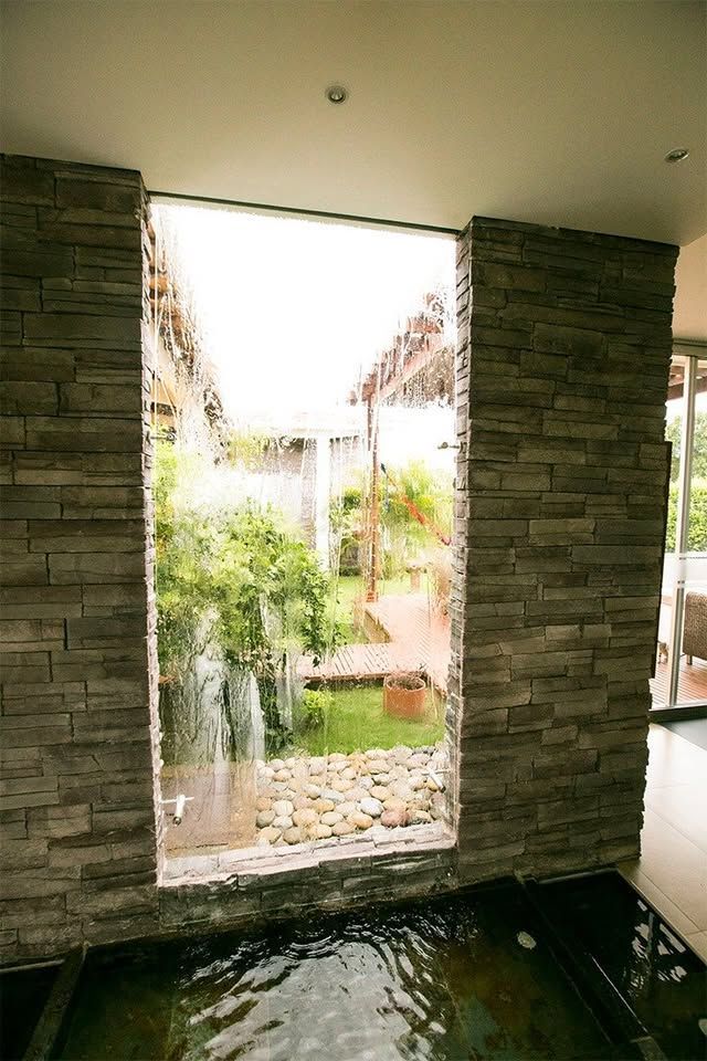 Recibidor de 18 m² con espejo de agua y cascada interior en muro de piedra